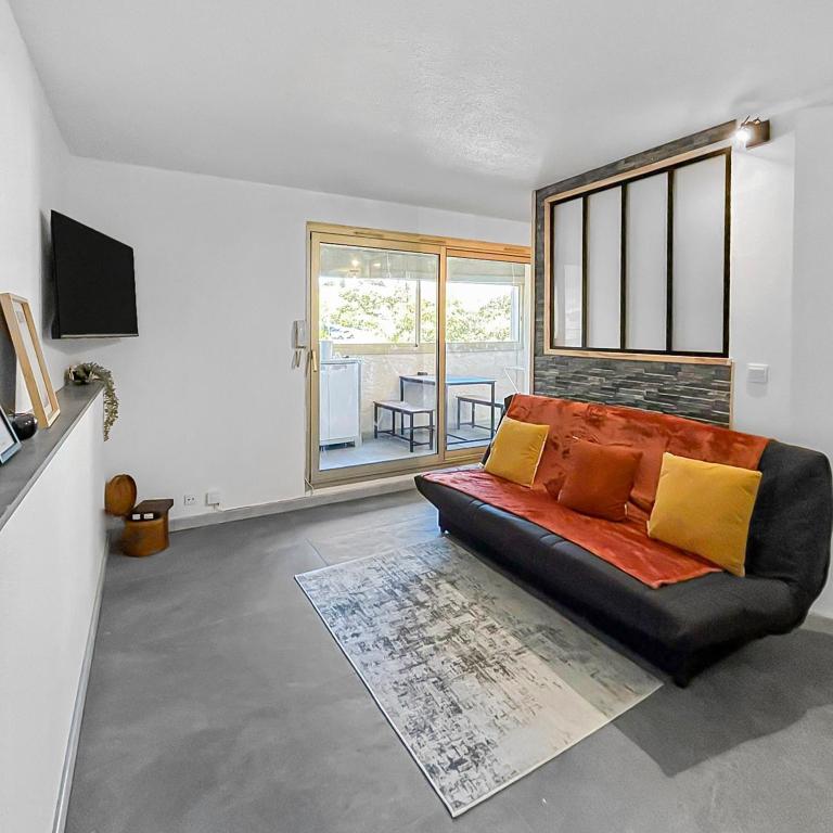 un canapé noir dans un salon avec une fenêtre dans l'établissement Retraite Romantique à Sainte-Maxime, à Sainte-Maxime