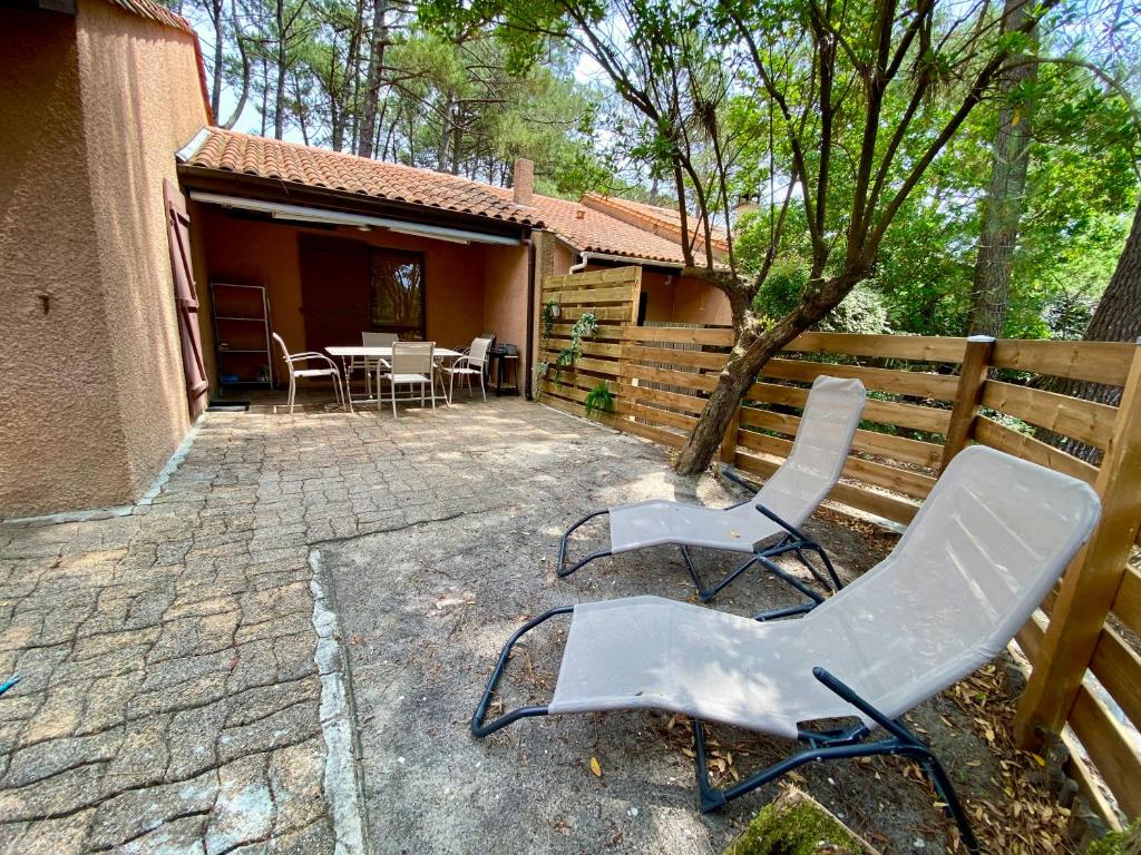 un patio avec des chaises et une table et une clôture dans l'établissement Maison au calme dans la pinède, à Lacanau
