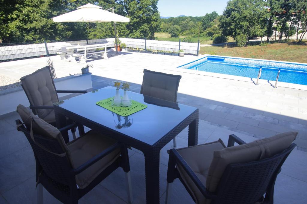 una mesa y sillas en un patio junto a la piscina en Apartment - CASA Adrianovo, en Ljubuški