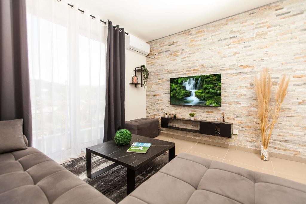 een woonkamer met een bank en een tv aan een bakstenen muur bij New Apartment in Vrnjačka Banja