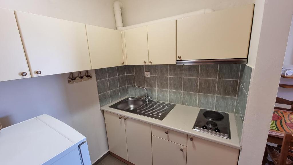 a small kitchen with white cabinets and a sink at Domatia me Thea in Elafonisos