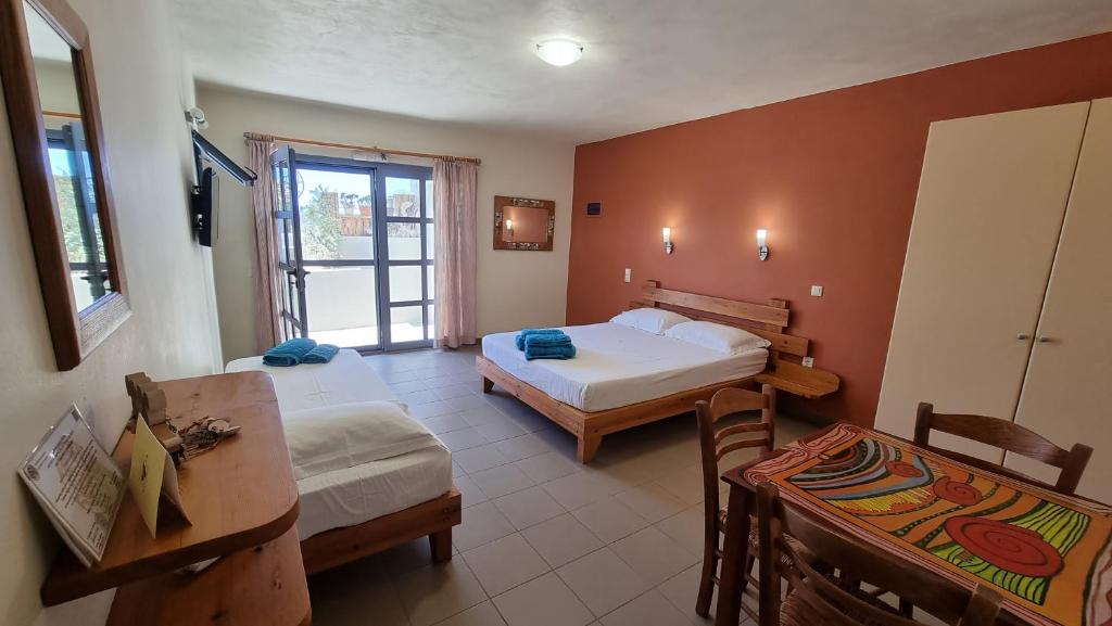 a hotel room with two beds and a table and chairs at Domatia me Thea in Elafonisos
