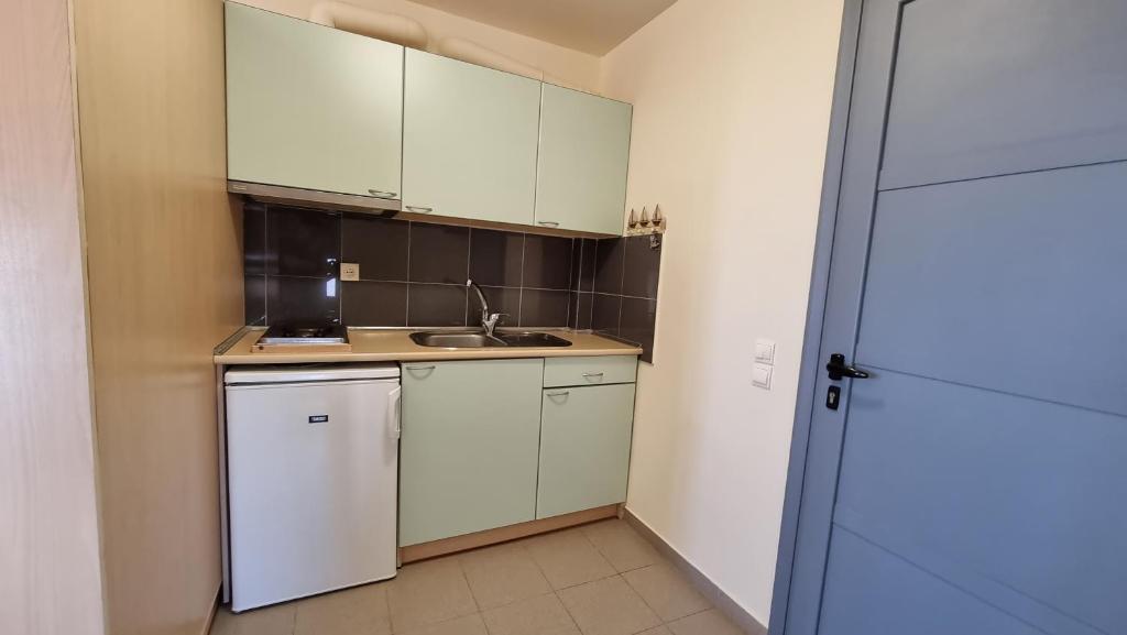 a small kitchen with white cabinets and a sink at Domatia me Thea in Elafonisos