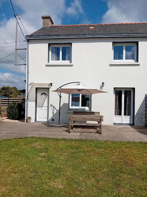 une maison blanche avec un banc et un parasol dans l'établissement Chez Jean Jacques, à Ploemeur
