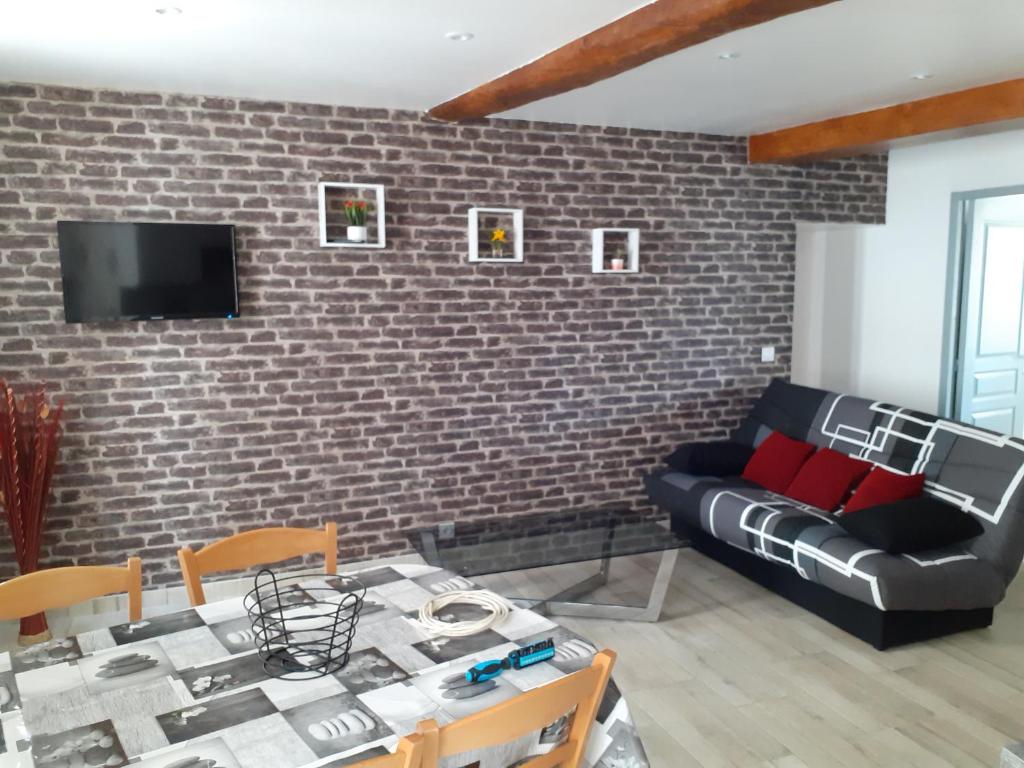a living room with a brick wall and a black couch at Appartement 80m2 in Castellane
