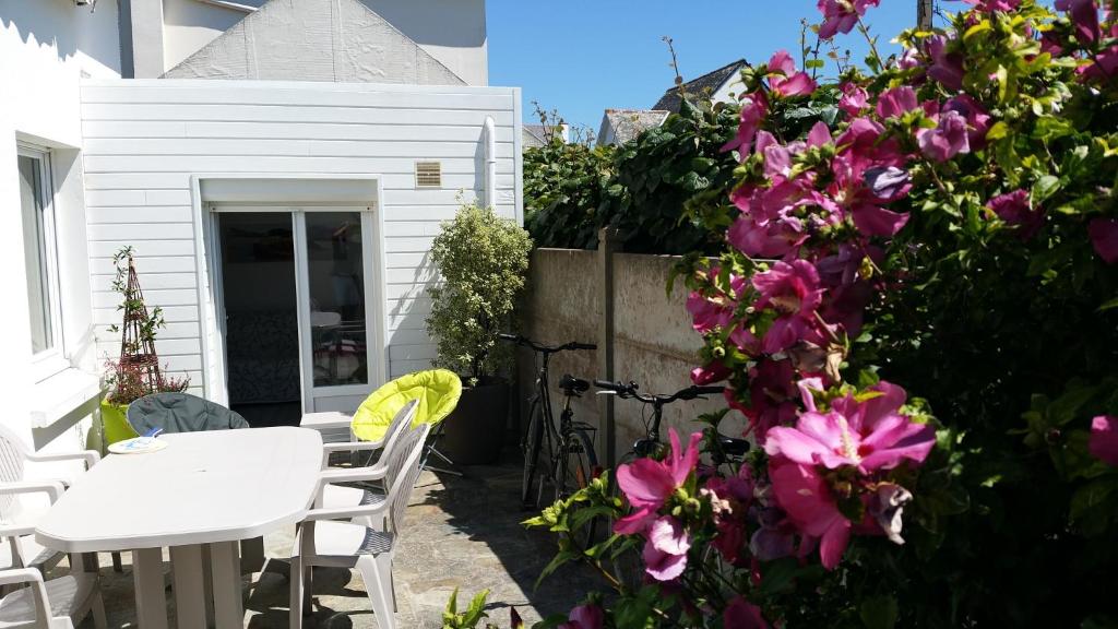 un patio avec une table blanche et des fleurs roses dans l'établissement Maison proche plage et côte sauvage, à Saint-Pierre-Quiberon