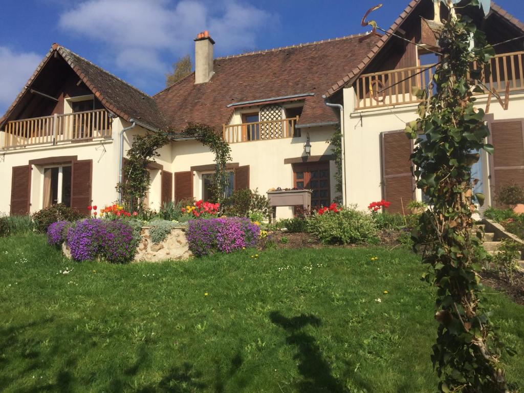 Une grande maison blanche avec des fleurs dans la cour dans l'établissement lacampagneenchantée, à Madeleine