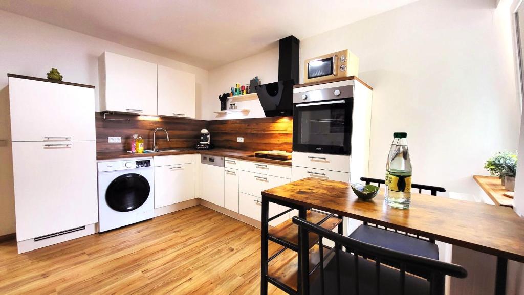 a kitchen with white cabinets and a wooden table at Apartment Stadtliebe Marburg PS4 in Marburg an der Lahn