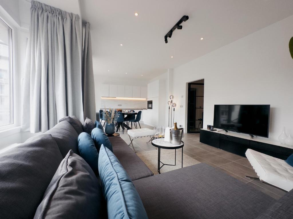a living room with a blue couch and a television at Seaside Living - Apartment Stella in De Panne