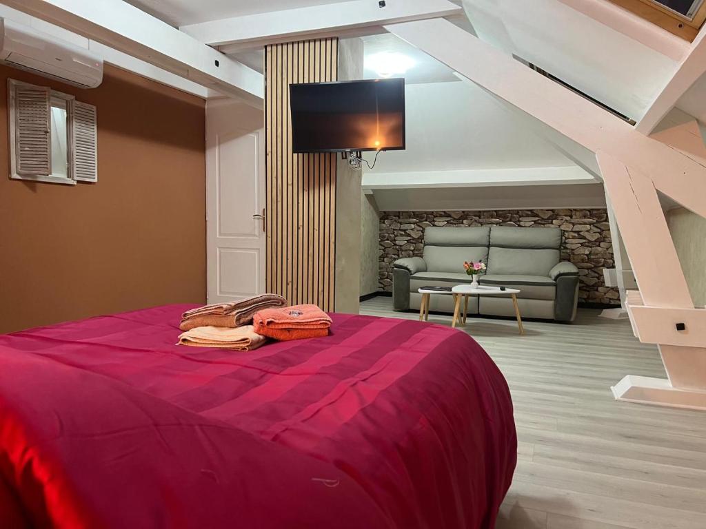 une chambre avec un lit rouge avec un canapé et une télévision dans l'établissement La Maison de Tina, à Lanzac