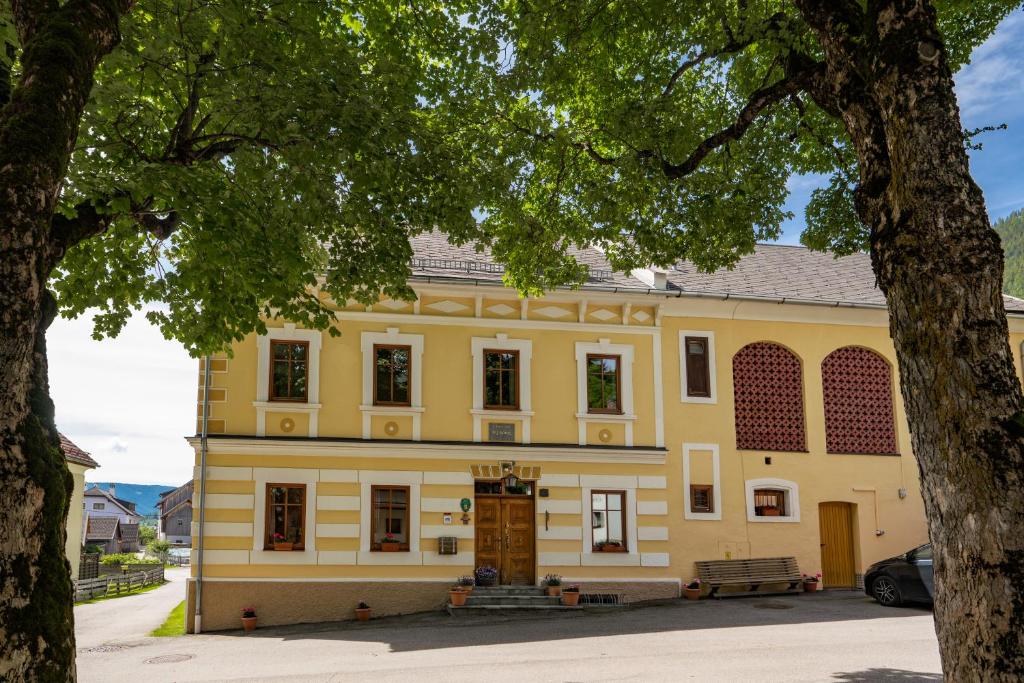 an old yellow building with a tree in front of it at Haus König in Mauterndorf