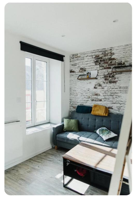 - un salon avec un canapé bleu et un mur en briques dans l'établissement La Débarque, à Cherbourg en Cotentin