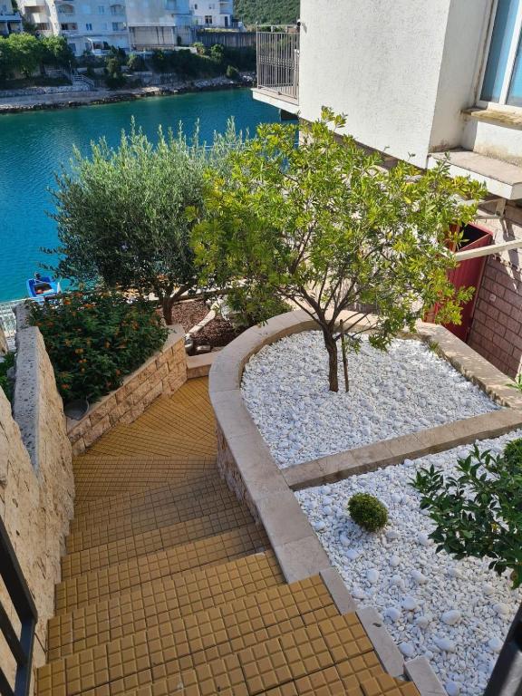 a garden with trees and rocks and water at Apartmani Niko in Neum