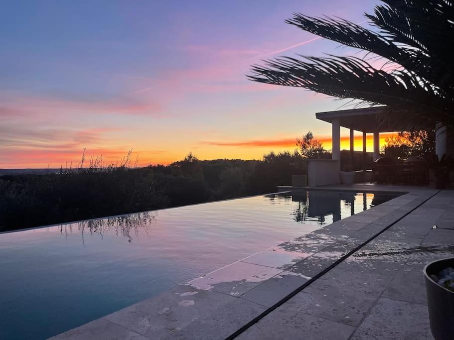 une piscine avec un coucher de soleil en arrière-plan dans l'établissement Maison californienne Nîmes, à Nîmes