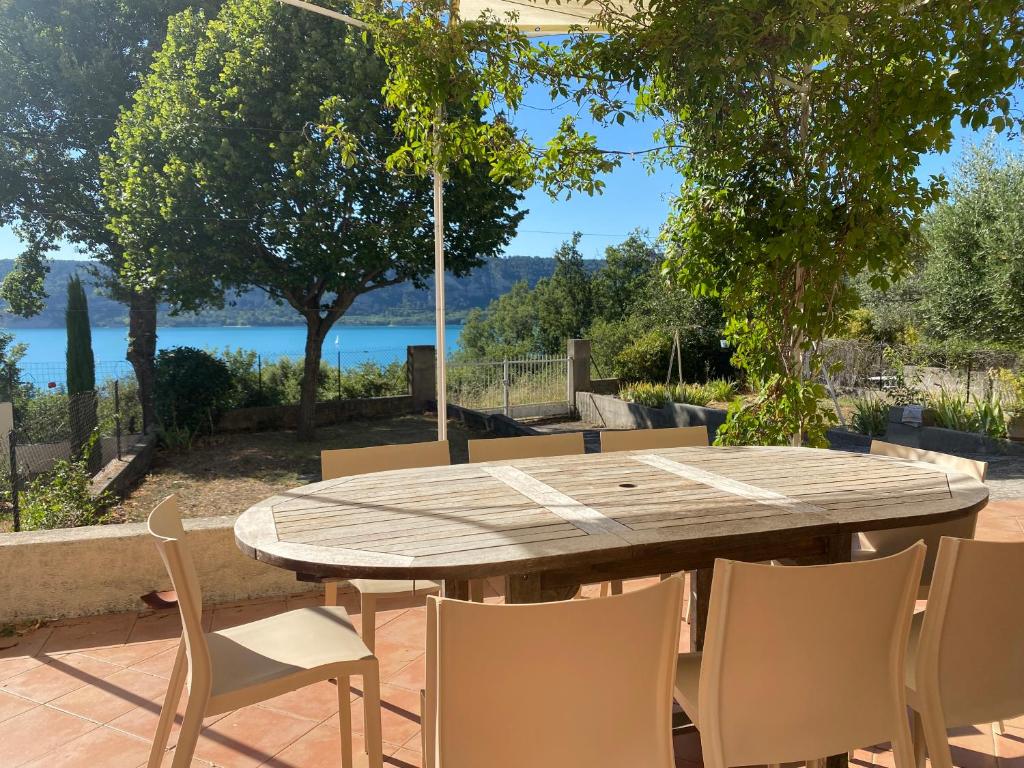 - une table et des chaises en bois avec vue sur l'eau dans l'établissement Maison Sainte Catherine, aux Salles-sur-Verdon