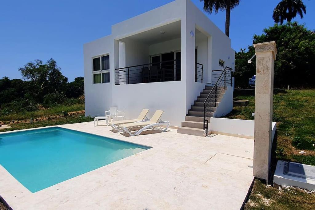 a house with a swimming pool in front of a house at 2 Bedroom Pool Villa in Gated Encuentro Residences by Palm Hills Real Estate in Cabarete