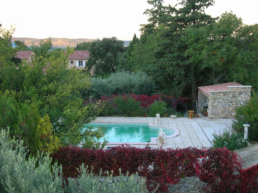 a swimming pool in the middle of a garden at Le Mas des Baux in Bédoin