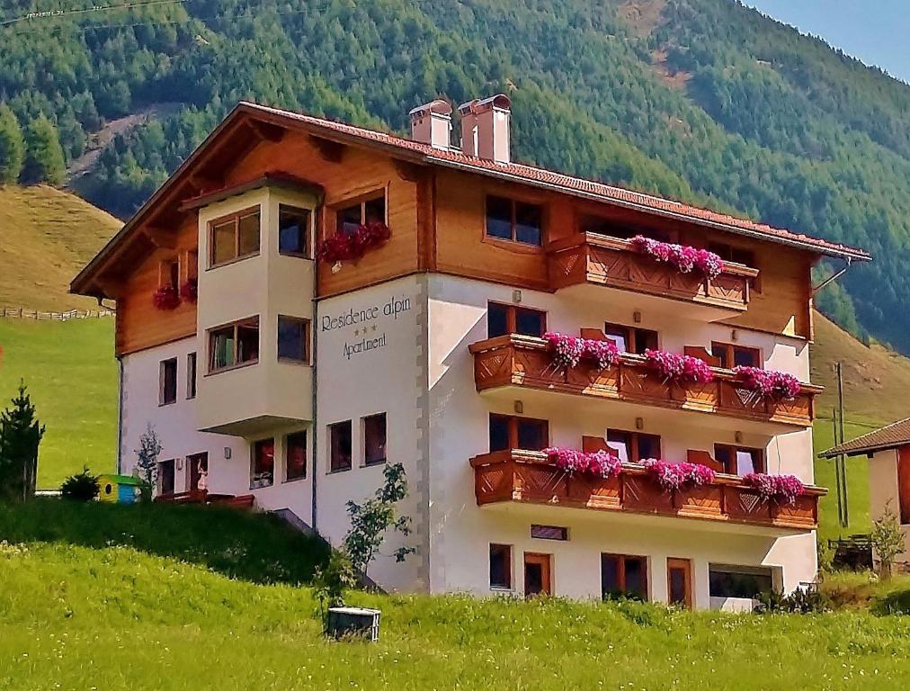 a building with flowers on the balconies of it at Residence Alpin in Melago