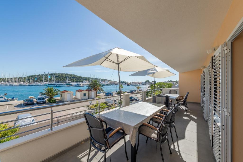 a balcony with tables and chairs and a view of the water at Seafront apartments Marija in Rogoznica