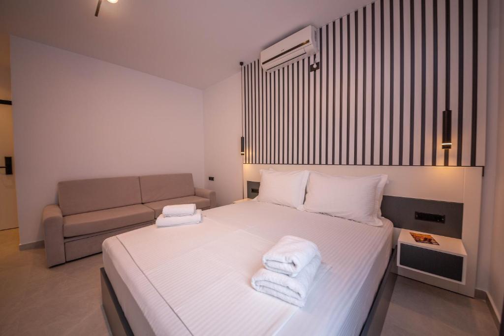 a bedroom with a bed with white sheets and a couch at Vila Olserd Shehu in Ksamil