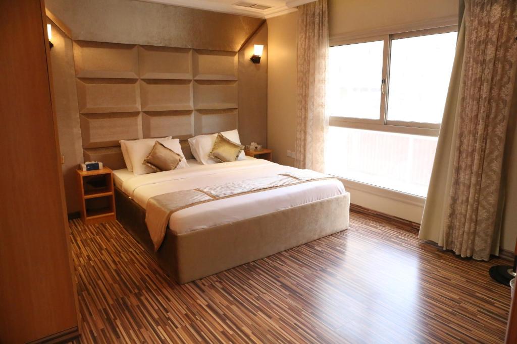 a bedroom with a large bed and a window at Terrace Furnished Apartments - Mahboula in Kuwait