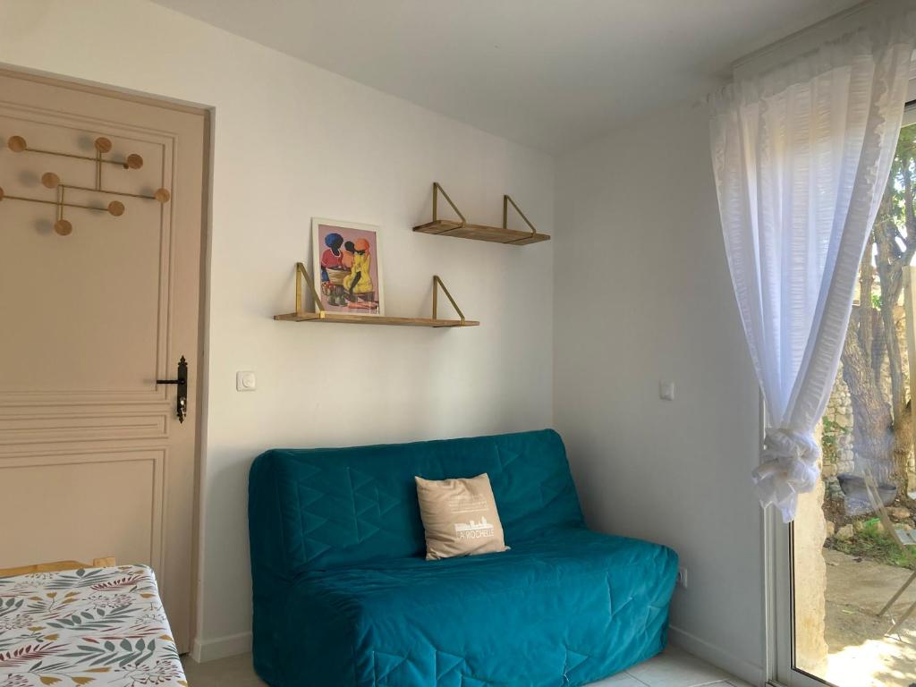 un canapé bleu dans une pièce avec une fenêtre dans l'établissement Charmante maison proche La Rochelle, à La Jarrie