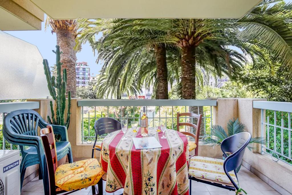 d'une table et de chaises sur un balcon avec des palmiers. dans l'établissement Cannes près Croisette beau 2 pièces 3 étoiles, à Cannes