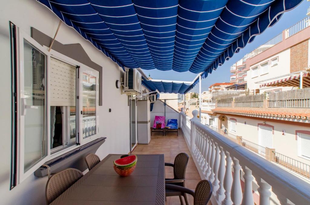 a balcony with a table with a bowl of watermelon on it at El Atico de Andrea in Torre del Mar