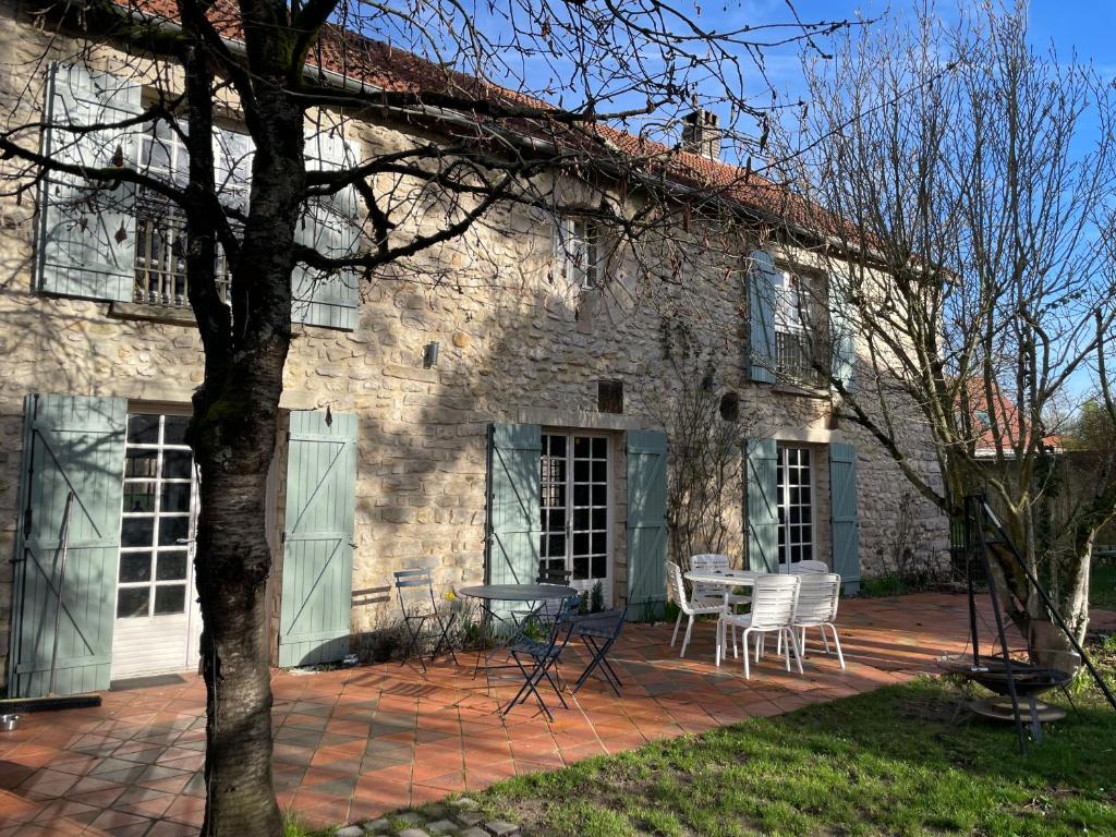 une maison en pierre avec des chaises et une table sur une terrasse dans l'établissement Maison de caractère, conviviale, à Boissy-le-Cutté