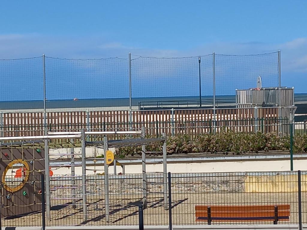 une clôture avec un banc en face d'une plage dans l'établissement Treportplage, au Tréport