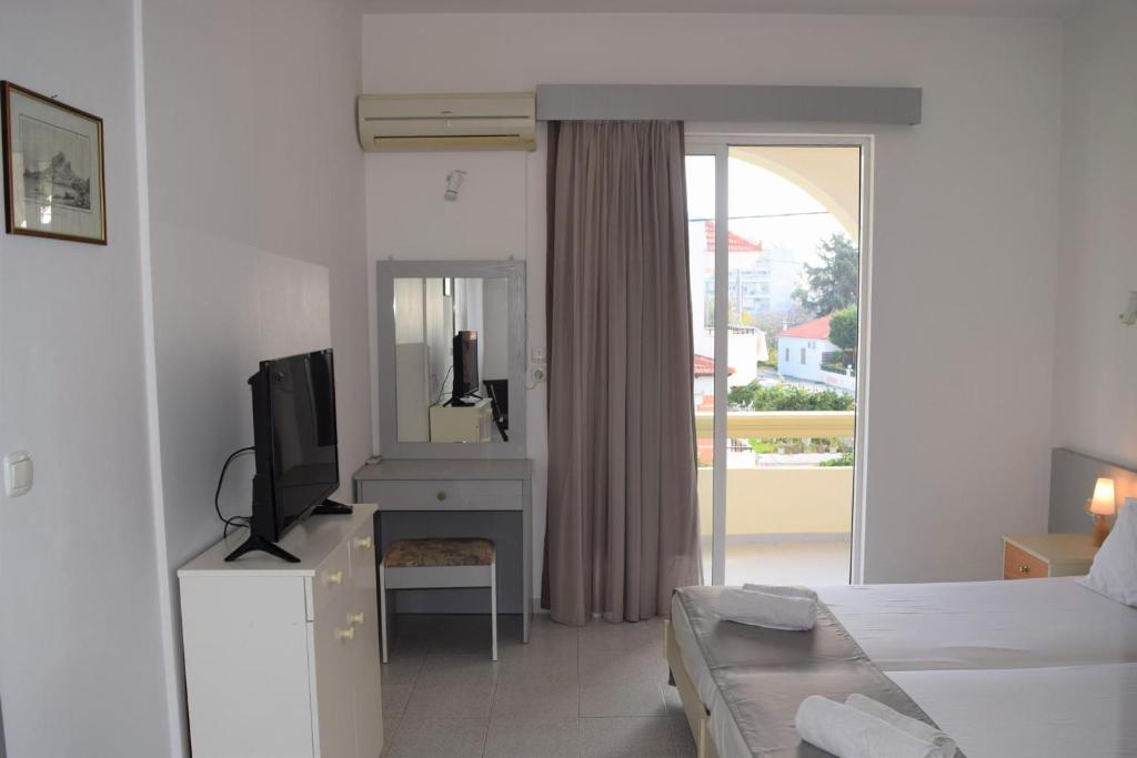 a bedroom with a bed and a tv and a mirror at Lefteris Apartments in Ialysos Rhodes in Ialyssos