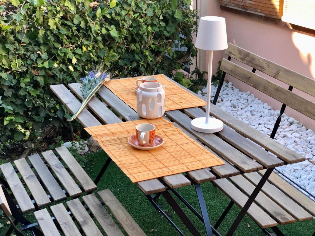 a wooden table with a cup of coffee on it next to two benches at Appartamento Aria D'Abete, Sirolo in Sirolo