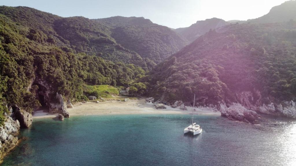 a boat in the water next to a beach at Limnionas Apartments in Xorychti