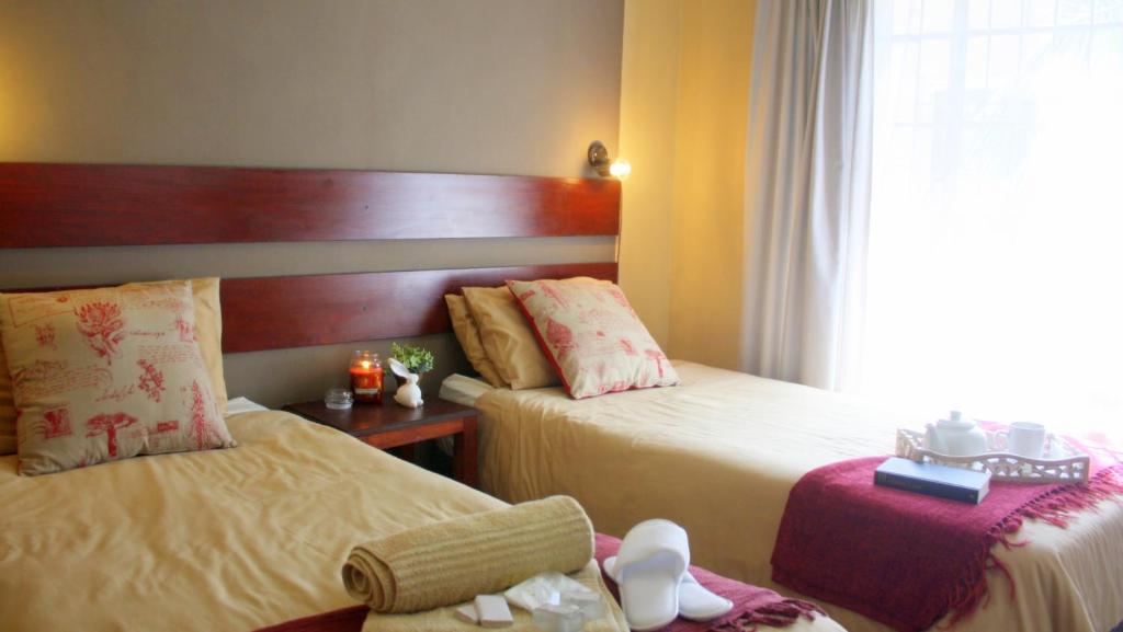 una camera d'albergo con due letti e una finestra di Honey Bee Guesthouse a Rustenburg