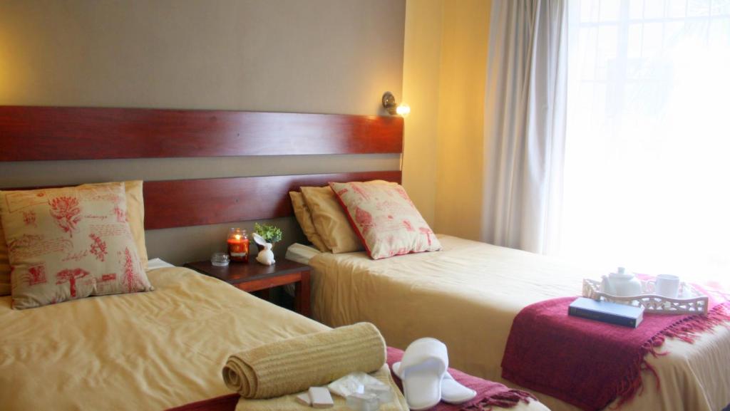 
a hotel room with two beds and two lamps at Honey Bee Guesthouse in Rustenburg
