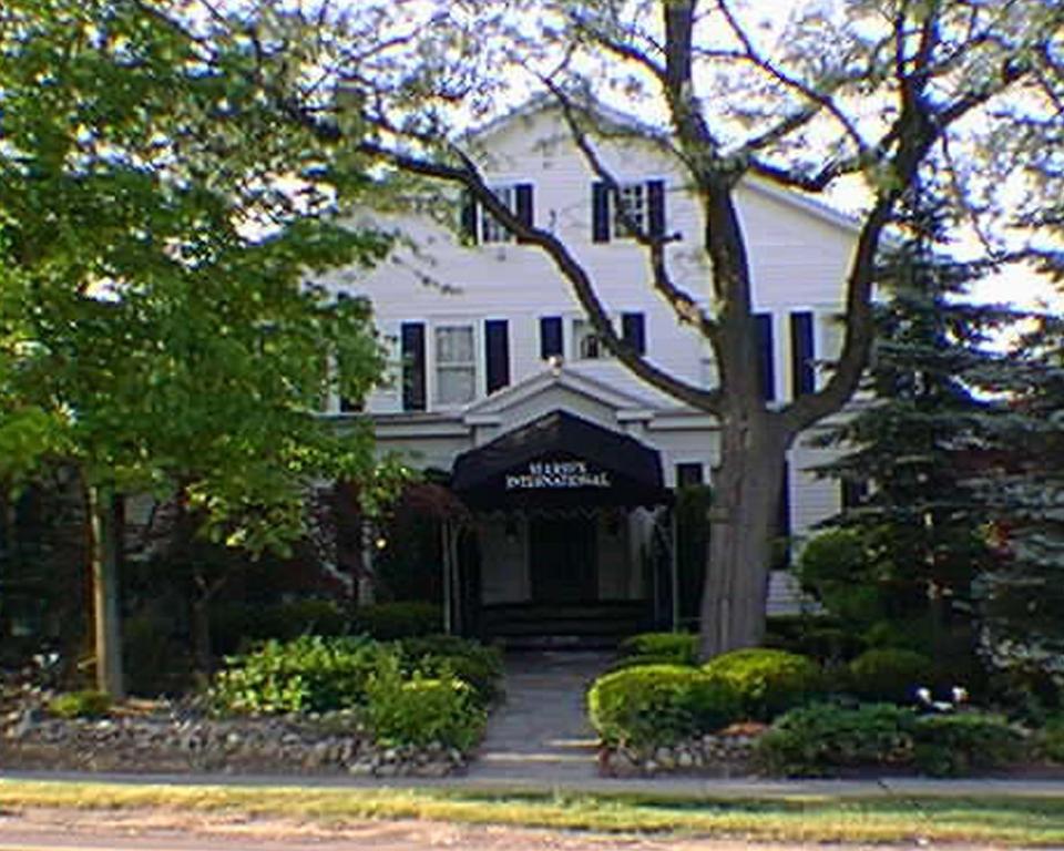 Una casa blanca con un árbol delante. en Mario's International Spa, Hotel & Restaurant, en Aurora