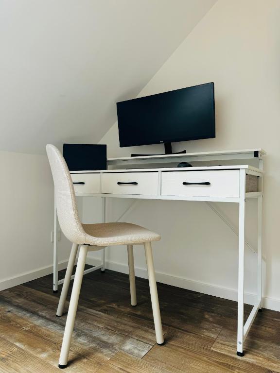 a white desk with a tv and a chair at Ganzes Tiny House "Thüringer Ruhe" mit großem Garten nahe Rennsteig in Laucha