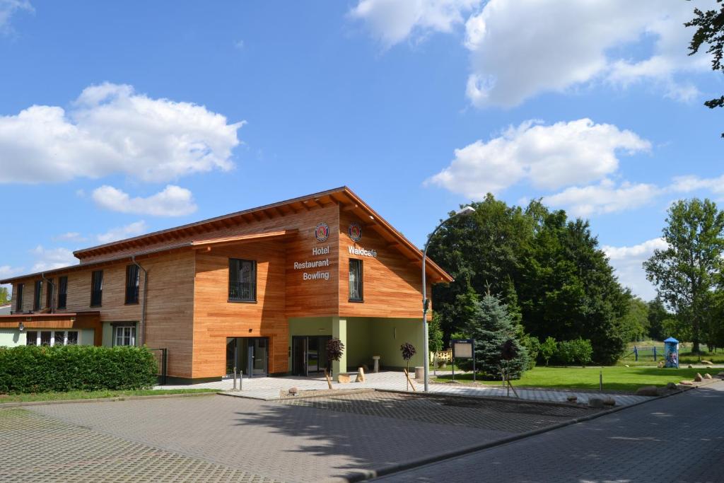 ein großes Holzgebäude an der Seite einer Straße in der Unterkunft Hotel & Restaurant Waldcafe Hettstedt in Hettstedt