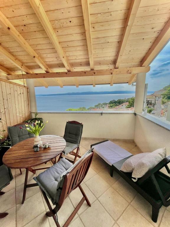a patio with a wooden ceiling and a table and chairs at Studio Katara Brela in Brela