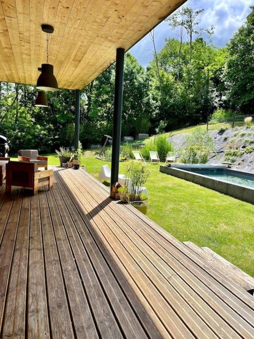 une terrasse en bois avec vue sur le jardin dans l'établissement Maison en bois au calme piscine, à Corbarieu