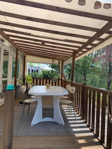 un porche avec une table blanche sur une terrasse dans l'établissement Coquet mobilhome climatisé, à Villeneuve-lès-Maguelone