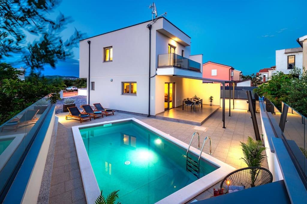 a house with a swimming pool in front of a house at Holiday home Val in Šibenik