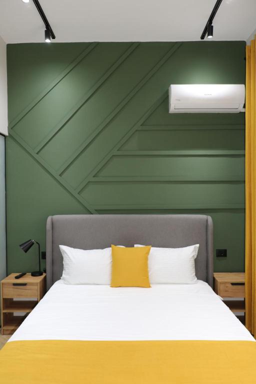 - une chambre dotée d'un lit avec un mur vert dans l'établissement City Center Rooms Durres, à Durrës