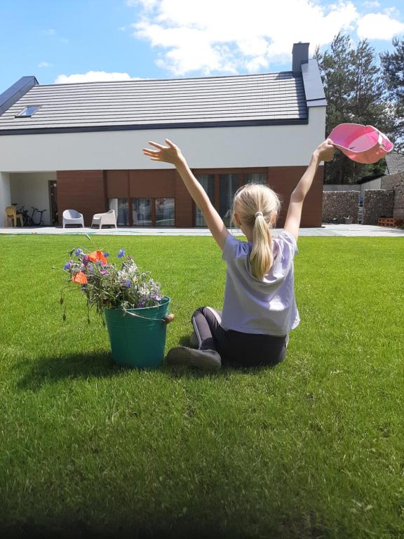 Una niña sentada en el césped con un frisbee en Skorzęcin Pachnie Miętą, en Skorzęcin