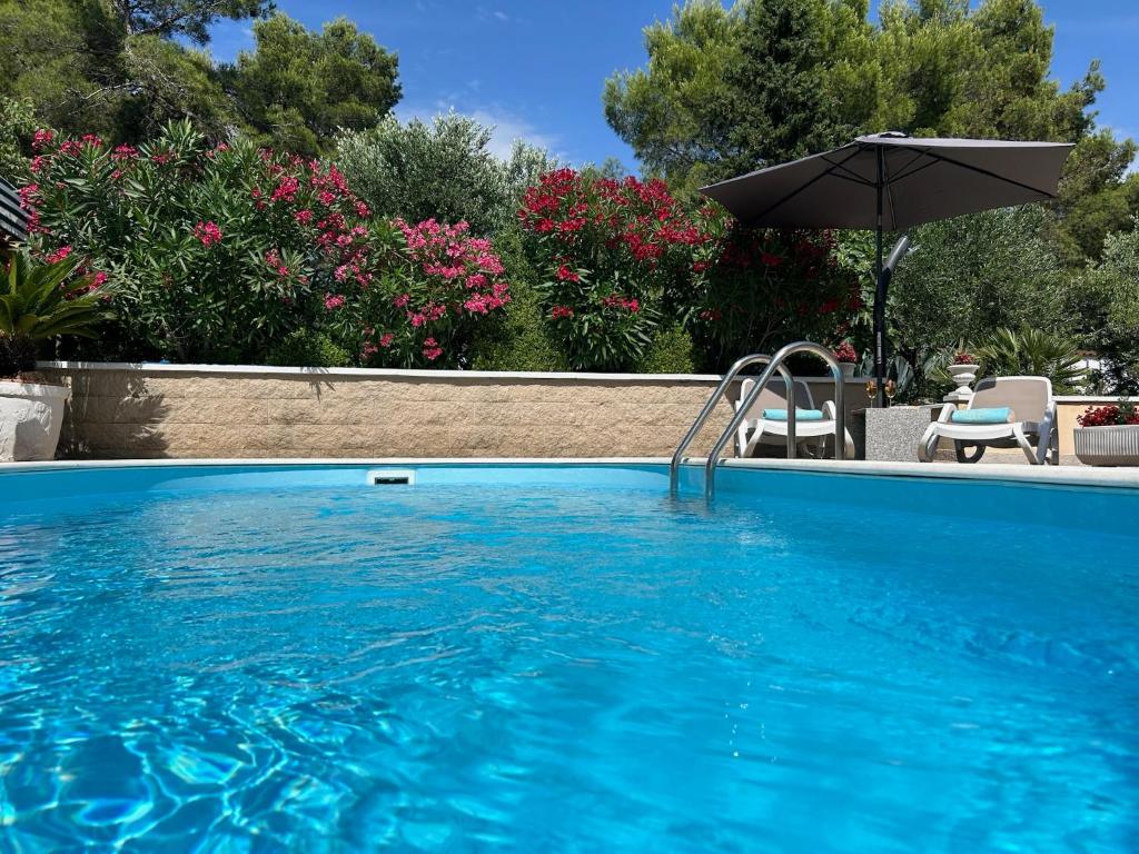 a large blue swimming pool with an umbrella at Holiday Home Villa Romantica in Sveti Filip i Jakov