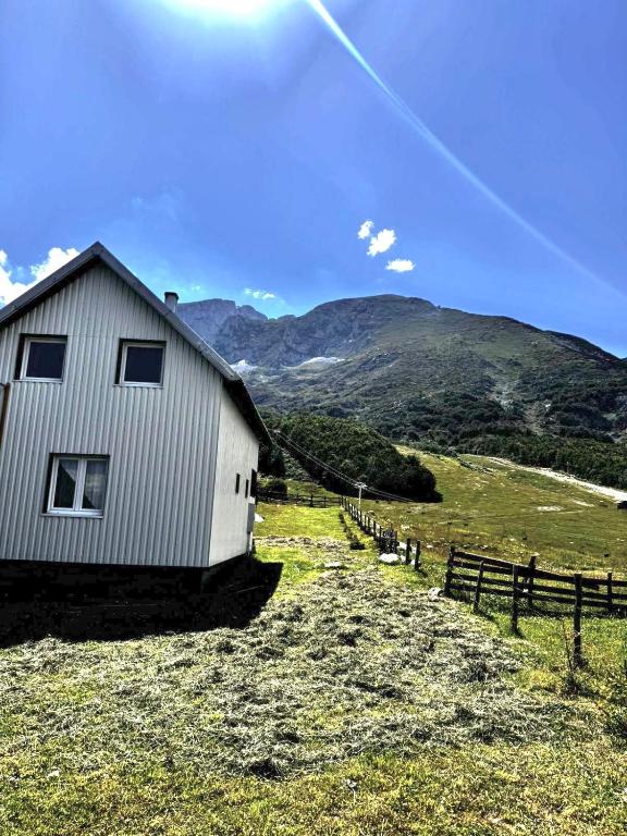 a white building in a field with a fence at Mountain house Savin Kuk in Žabljak