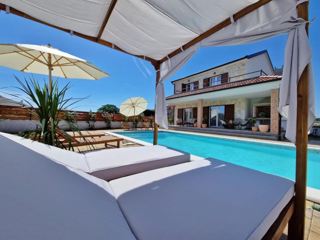 una piscina con dos tumbonas y una sombrilla en Rustic House Konfidenca, en Biograd na Moru