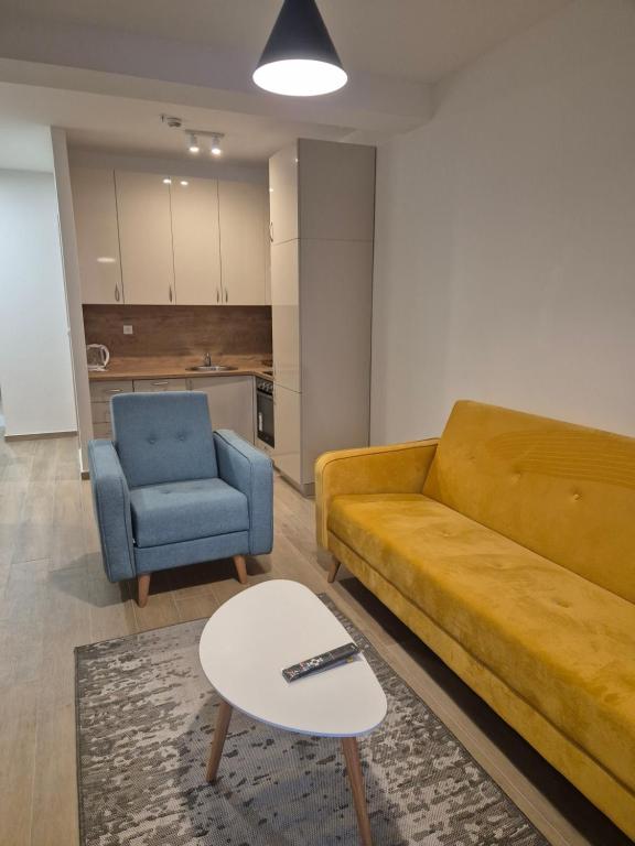 a living room with a yellow couch and a blue chair at Rafailovici Beachfront Apartment 2 in Budva