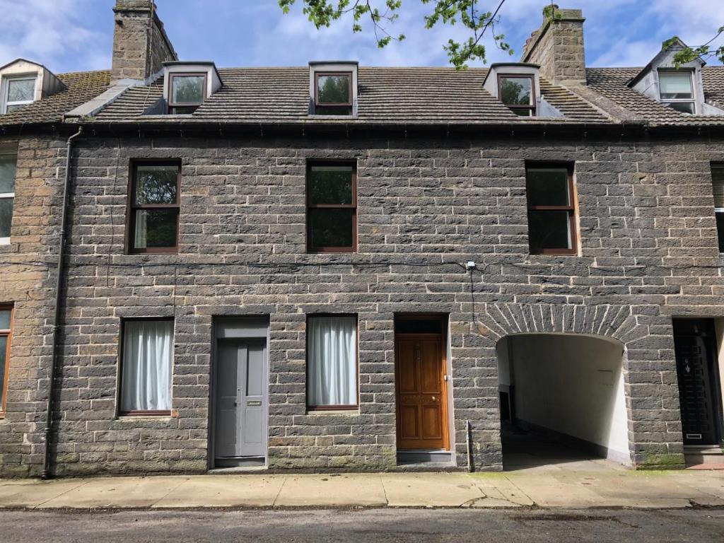 an old brick house with a brown door at 4 bed Harbour House in Wick