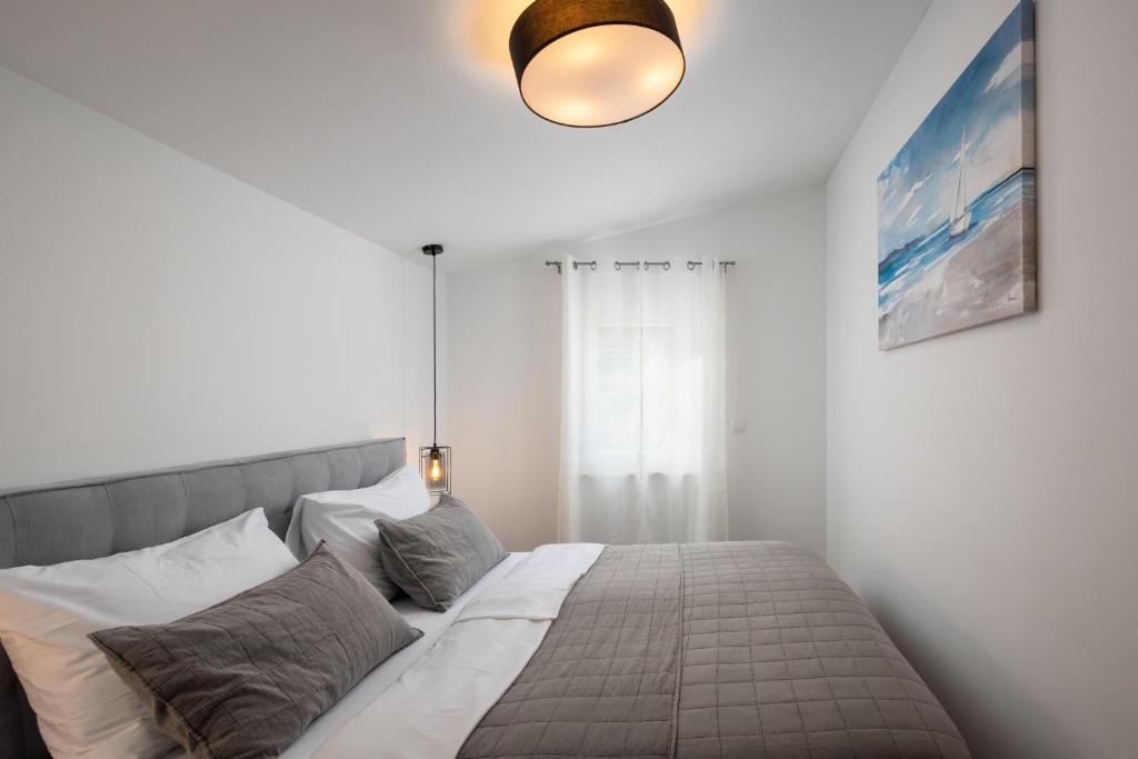 a bedroom with a bed in a white room at Villa Mala Smišna Poolside Paradise by the Sea in Maslinica